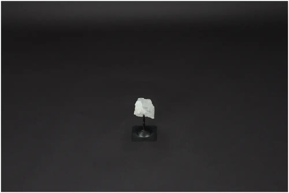 Lemurian Quartz on metal stand against a dark background, promoting clarity and energetic purification by absorbing negative vibrations.