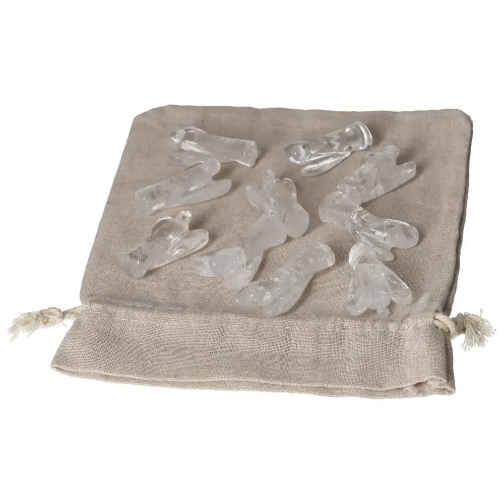 Clear Quartz Lemurian Small Angel figurines on beige cloth bag, harmonizing energy and neutralizing negative vibrations.