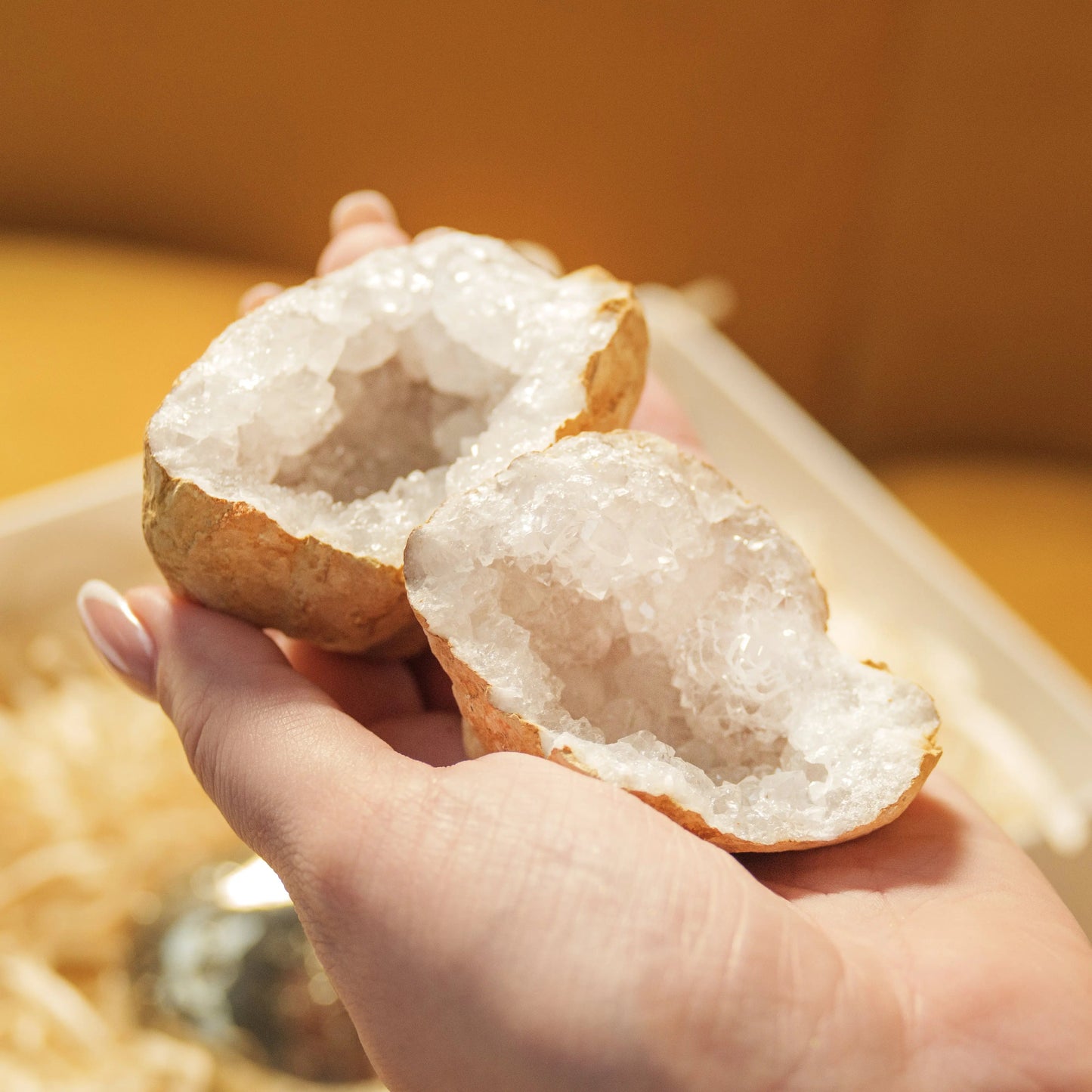 Hand holding a split geode with sparkling crystals inside, part of the Love and Wealth Gift Box from Sylvia Crystals.