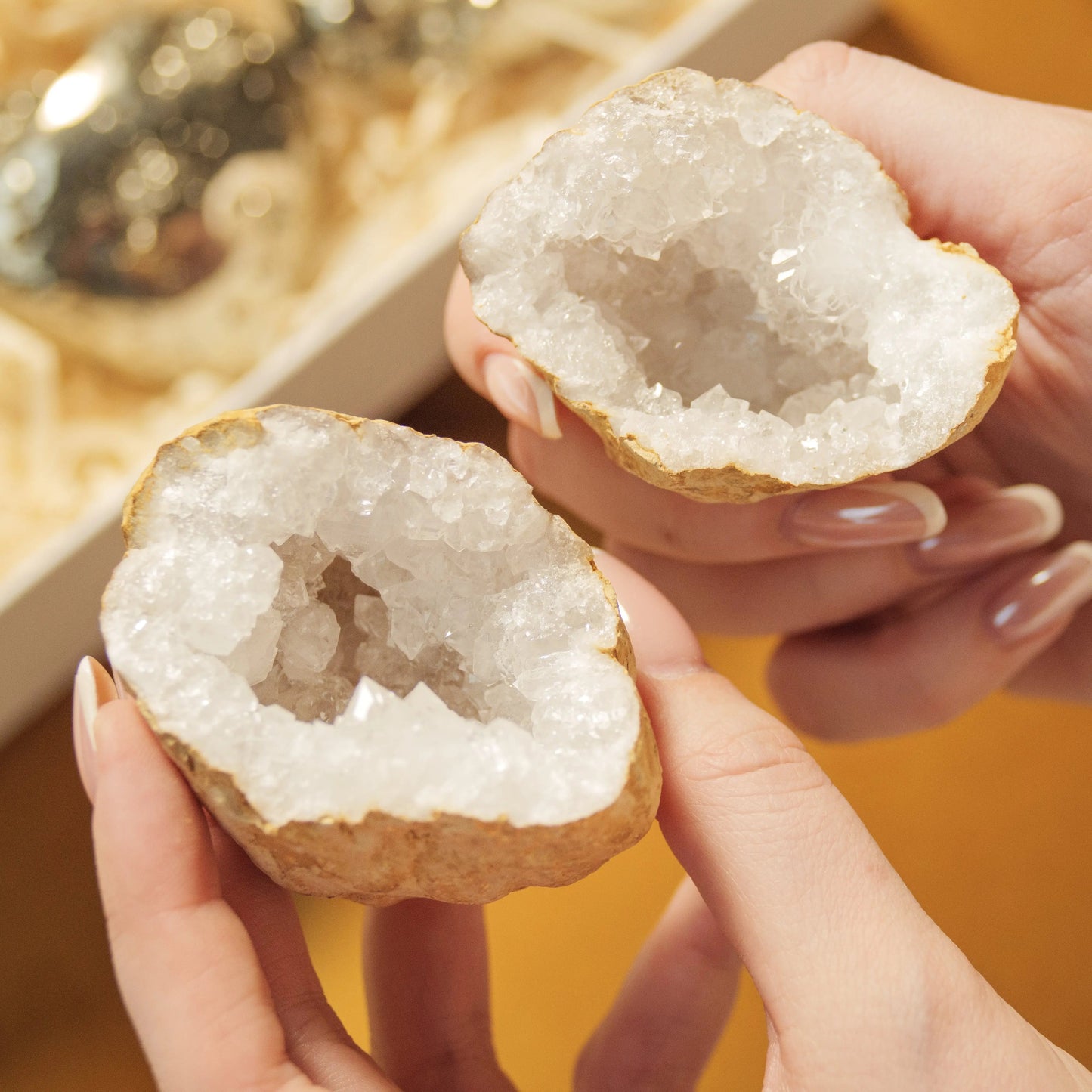 Hands holding two sparkling geodes from the Love and Wealth Gift Box, symbolizing love and prosperity by Sylvia Crystals.