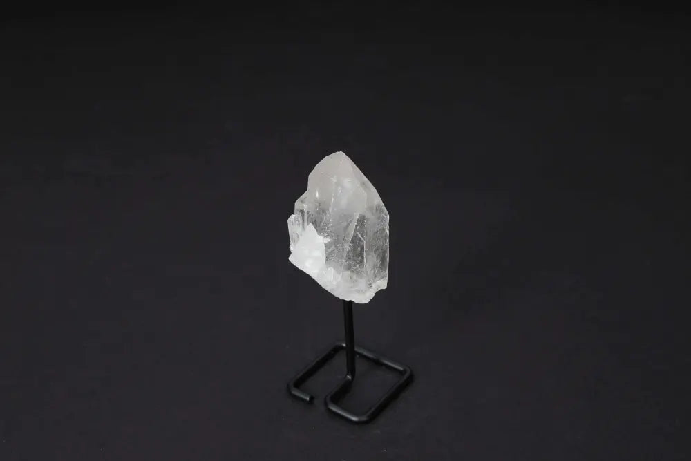 Clear Quartz Point on stand, amplifying energy and clarity, ideal for meditation and manifestation, displayed on dark background.