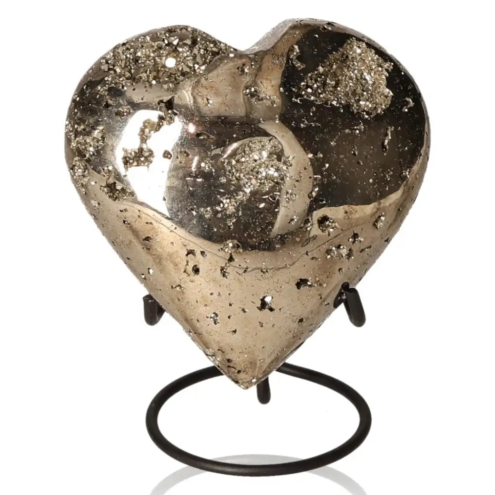 Heart-shaped pyrite stone, known as Fool's Gold, with a metallic luster symbolizing abundance and prosperity on a stand.