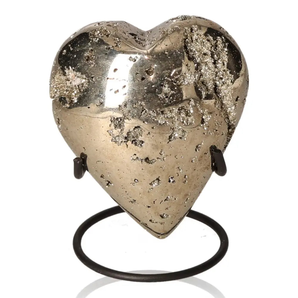 Heart-shaped pyrite stone with metallic luster, symbolizing wealth and prosperity, displayed on a stand.