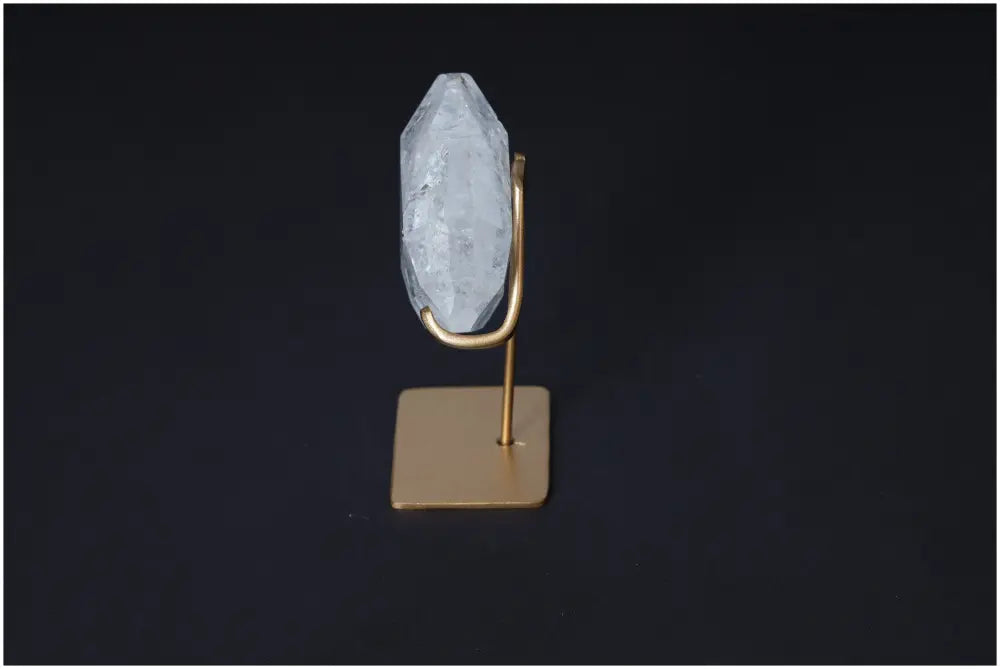 Clear Quartz Geometric Heart on a gold stand against a dark background, exemplifying purification and harmonizing energy properties.