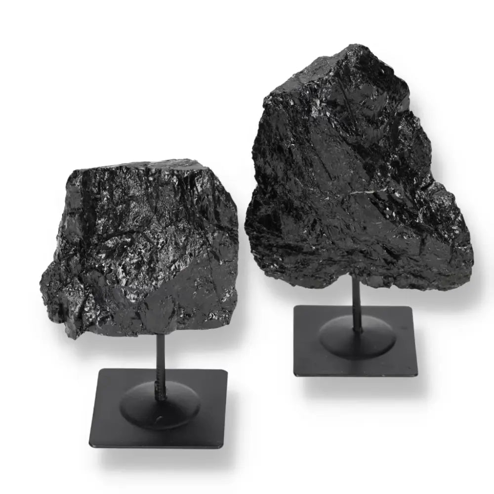 Rough black tourmaline crystals on metal stands, ideal for protection and grounding, showcased by Sylvia Crystals.