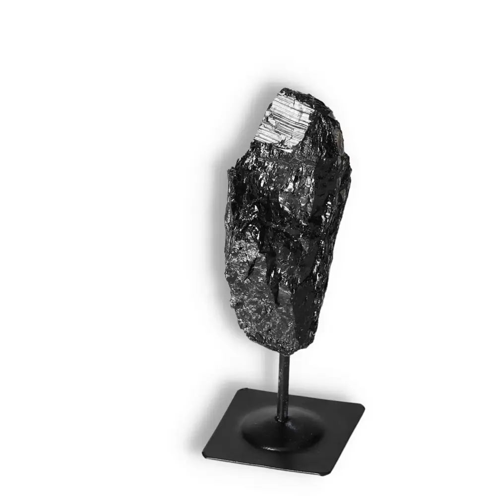 Rough Black Tourmaline on metal stand, offered by Sylvia Crystals, known for cleansing negative energies and spiritual elegance.