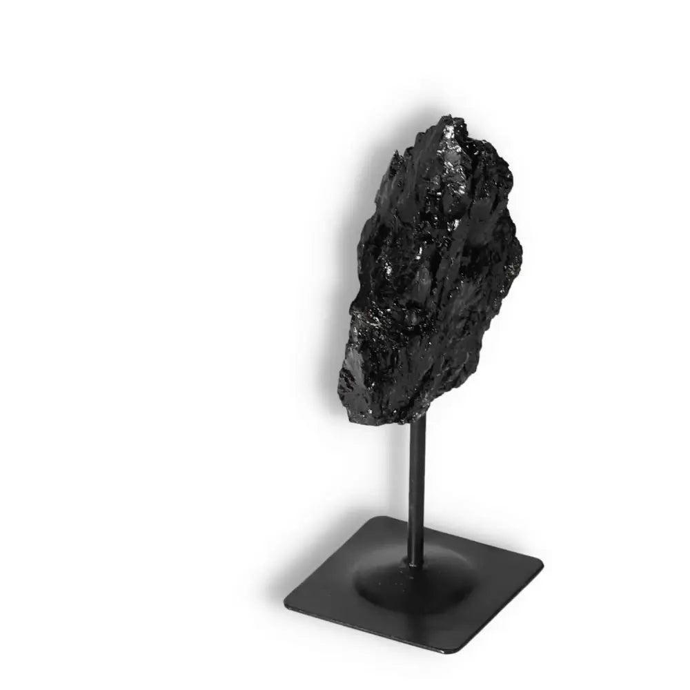 Rough Black Tourmaline with a metal stand by Sylvia Crystals, known for cleansing and transforming negative energies.