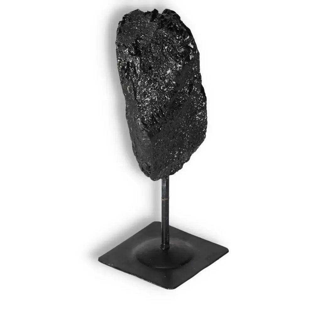 Rough Black Tourmaline on metal stand, a premium crystal from Sylvia Crystals for energy purification and transformation.