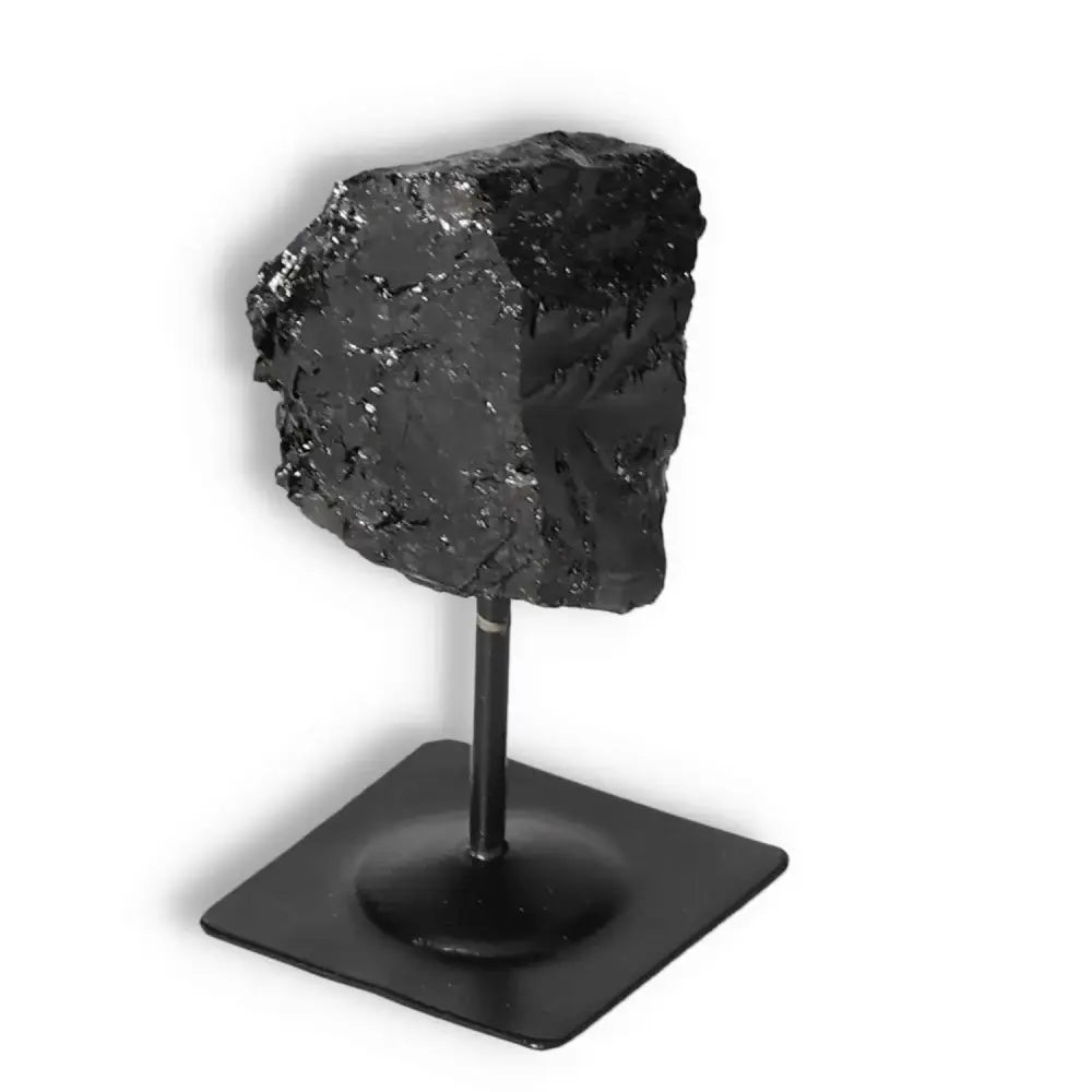Rough Black Tourmaline on a sleek metal stand, offering cleansing energy and natural beauty from Sylvia Crystals.