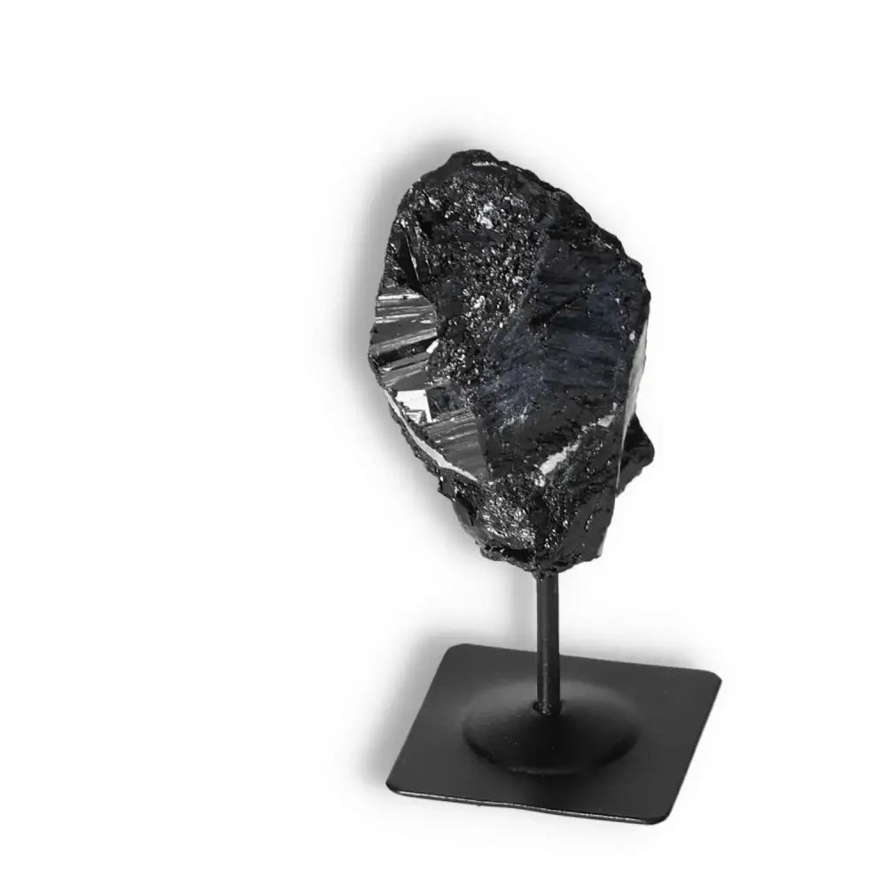 Rough black tourmaline crystal on metal stand from Sylvia Crystals, known for cleansing negative energies and exceptional quality.