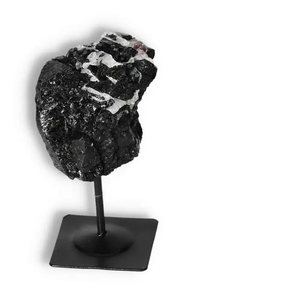 Rough Black Tourmaline crystal on a metal stand, offering cleansing and neutralizing energy from Sylvia Crystals.
