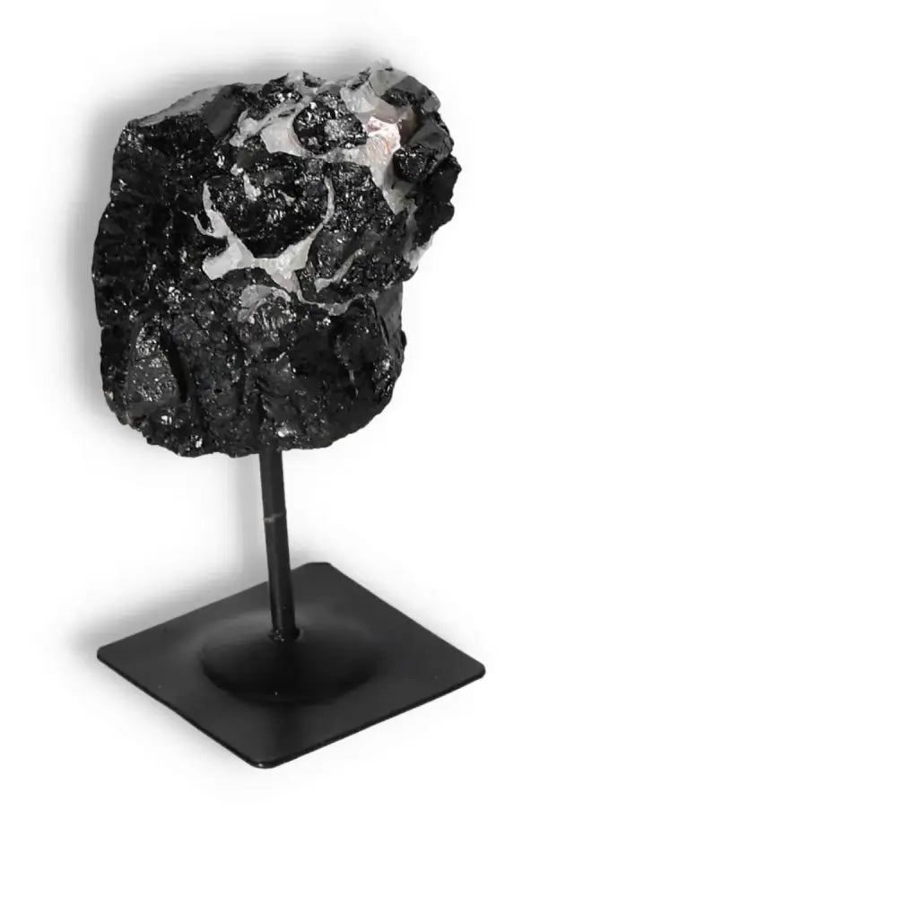 Rough black tourmaline crystal on metal stand, Sylvia Crystals, known for energy cleansing and elegance.