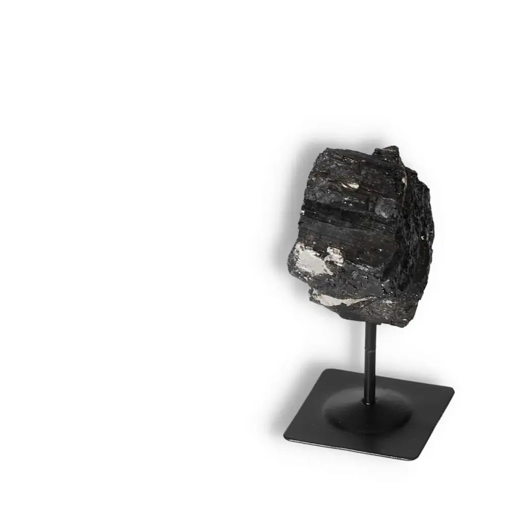 Rough Black Tourmaline on metal stand by Sylvia Crystals, known for grounding and purifying energies. Enhance concentration with this gemstone.