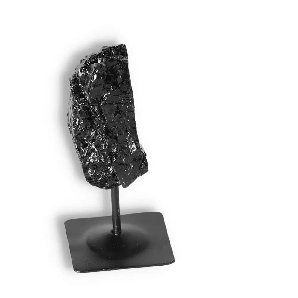 Rough Black Tourmaline on metal stand, elegant crystal decor by Sylvia Crystals, known for cleansing and transforming energies.
