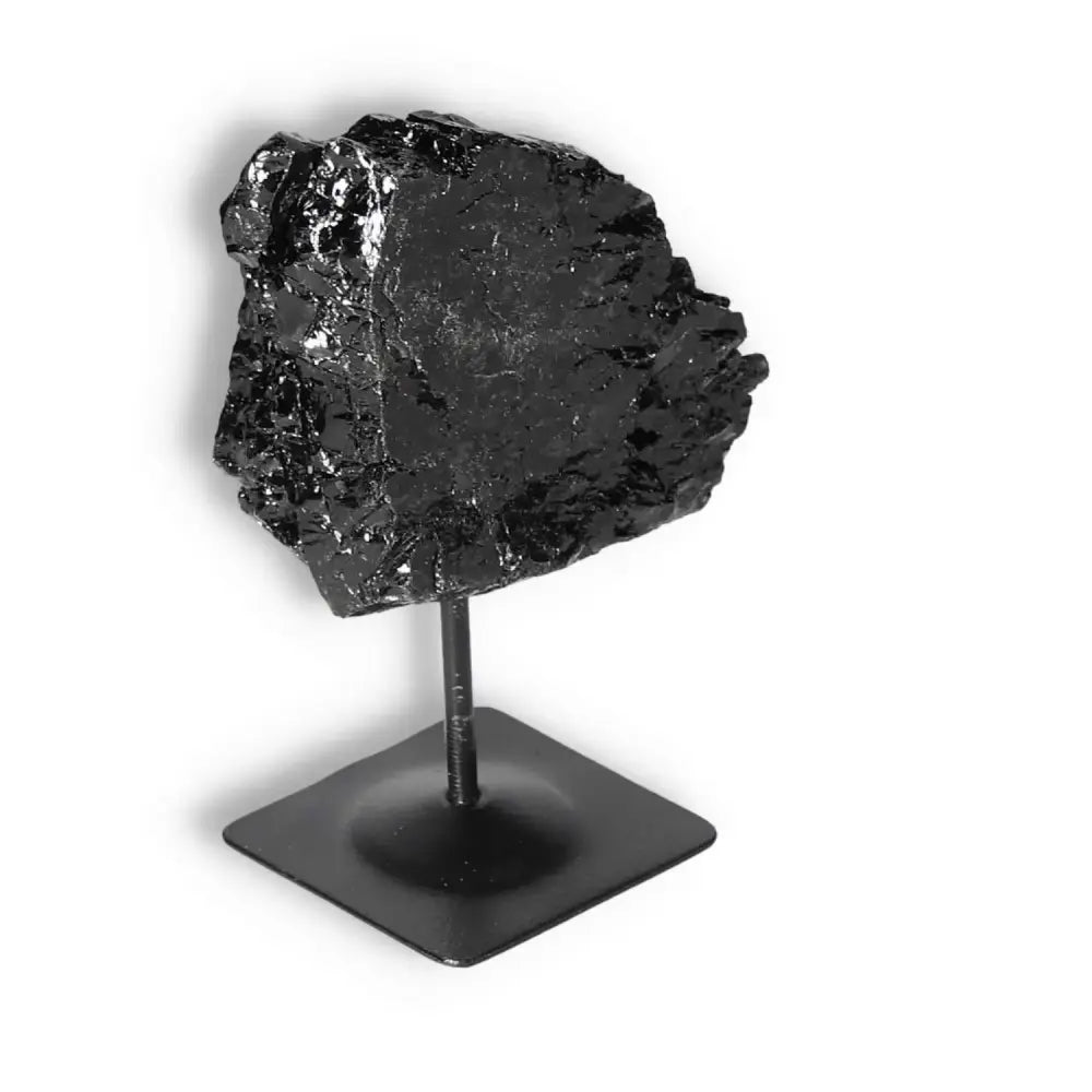 Rough Black Tourmaline on metal stand from Sylvia Crystals, known for transforming negative energies and providing grounding.