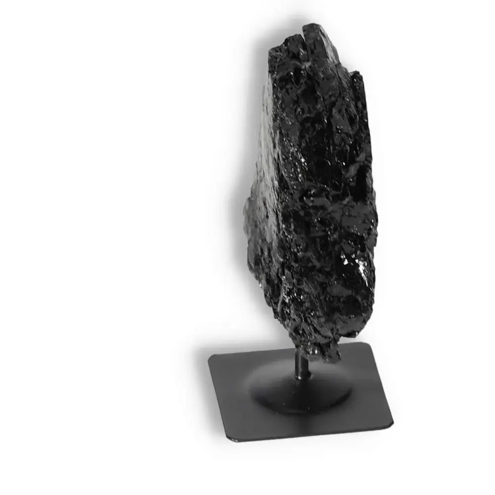 Rough black tourmaline on metal stand, premium crystal by Sylvia Crystals, known for cleansing energies and providing grounding stability.