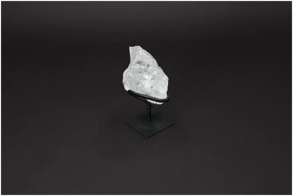 Rough Lemurian Quartz on sleek metal stand, showcasing clear crystal's natural beauty and spiritual allure by Sylvia Crystals.