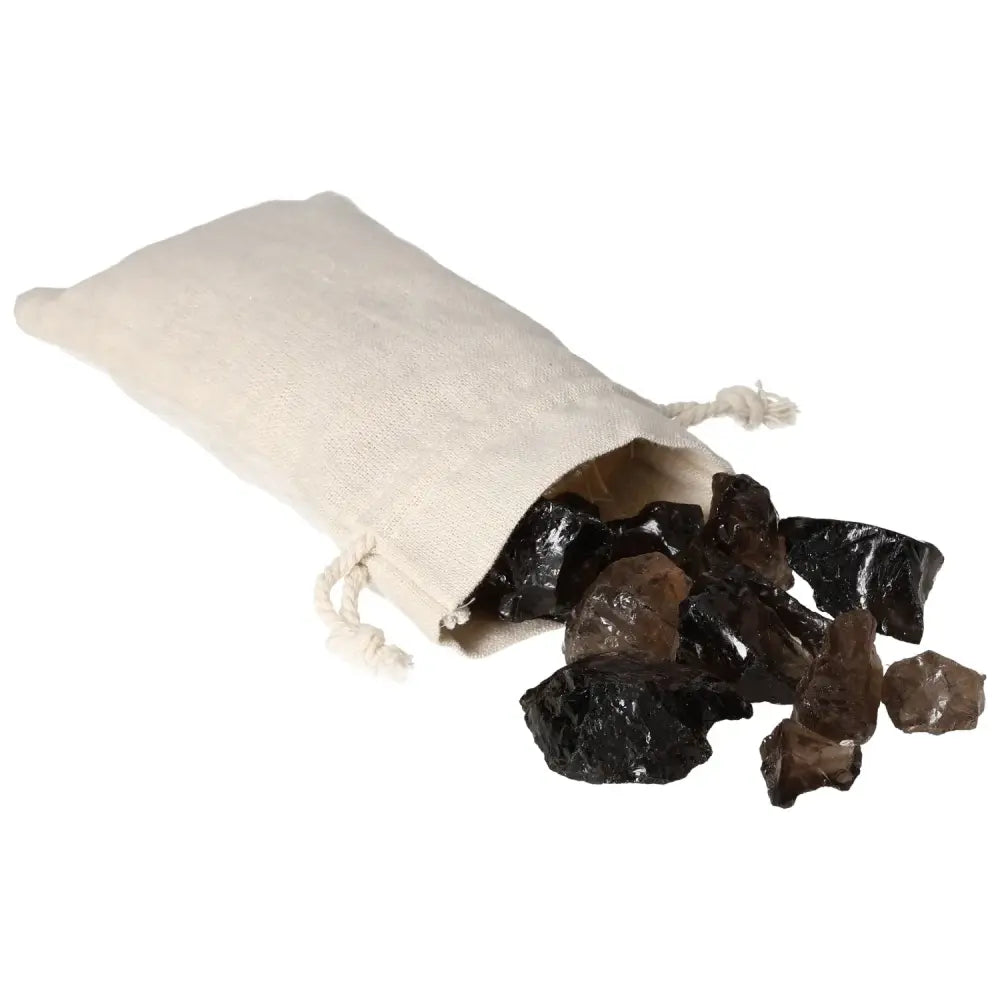 Pile of Rough Smoky Quartz gemstones spilling from a small beige drawstring pouch, showcasing their natural, uneven forms and dark tones.