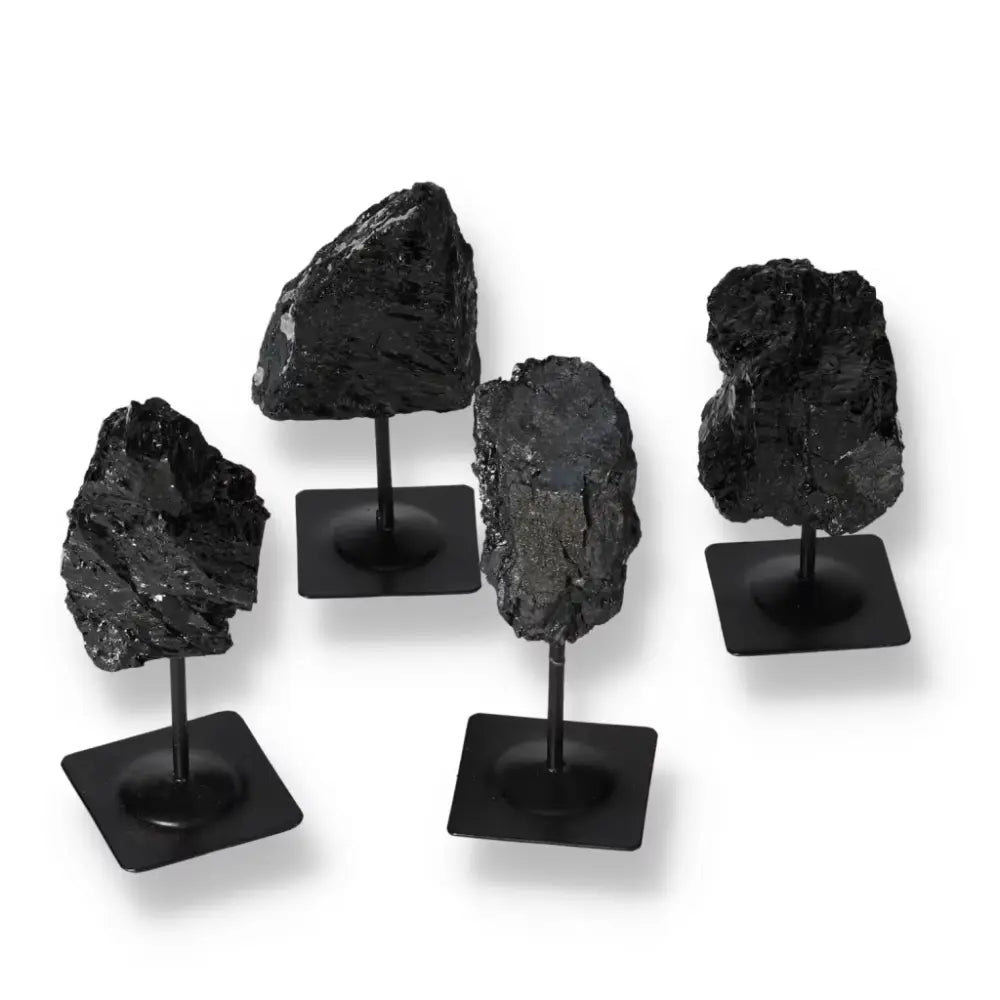 Rough Tourmaline stones on metal stands showcasing deep blacks and greens, from Sylvia Crystals, symbolizing luxury and spiritual harmony.