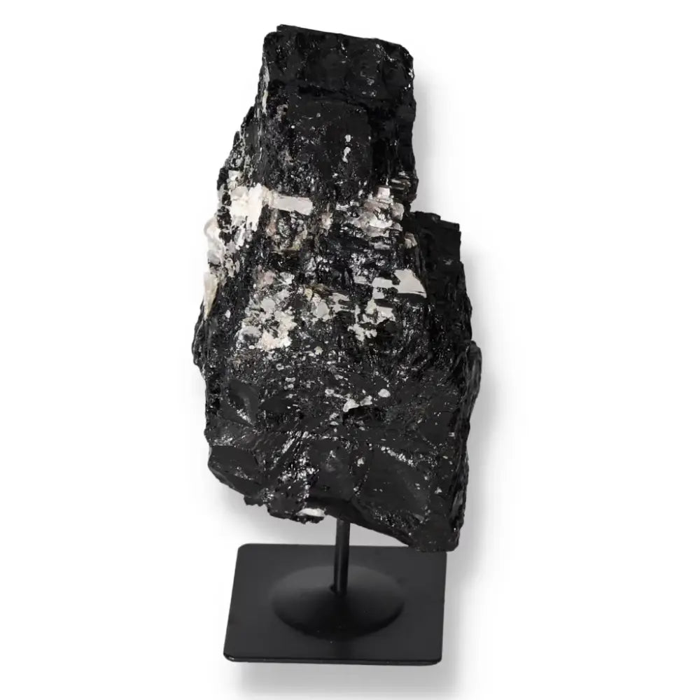 Rough tourmaline stone with unique formations on a sleek metal stand, perfect for interior decor by Sylvia Crystals.