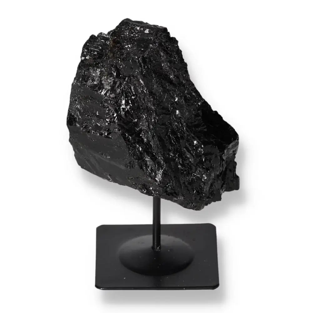 Rough black tourmaline stone on metal stand from Sylvia Crystals, showcasing energy-balancing properties and elegant display.