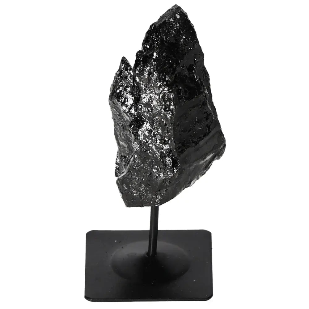 Rough black tourmaline crystal on metal stand for energy balance and natural decor.