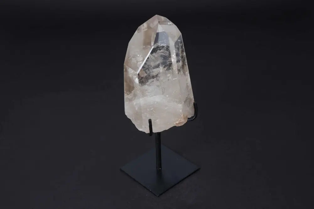 Semi polished clear quartz point on a modern black stand, ideal for energy amplification and meditation.