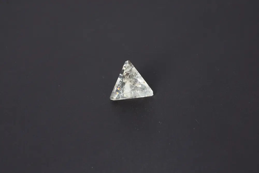 Clear crystal pyramid on a dark background showcasing its geometric shape and reflective surface.