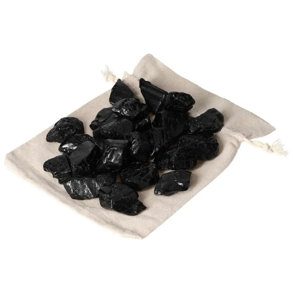 Tumbled Black Tourmaline stones on a beige cloth, part of Sylvia Crystals' 1KG 20PCS set, known for grounding and energy cleansing.