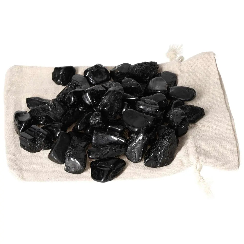 Tumbled Black Tourmaline M stones on a cloth, known for shielding negative energies and enhancing mental clarity from Sylvia Crystals.