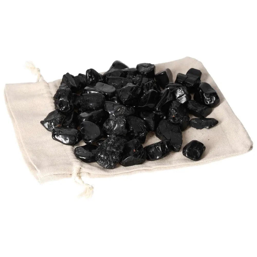 Tumbled Black Tourmaline stones on cloth, offering protection against negative energies and grounding, from Sylvia Crystals.