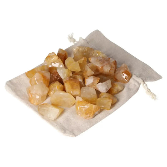 Tumbled Yellow Hematoide crystals on a white cloth, showcasing their golden hues, symbolizing elegance and spiritual harmony by Sylvia Crystals.