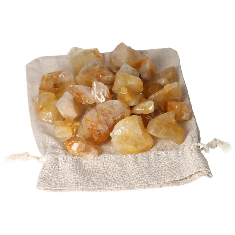 Tumbled Yellow Hematoide crystals on a white bag, showcasing golden hues and elegance from Sylvia Crystals' premium collection.