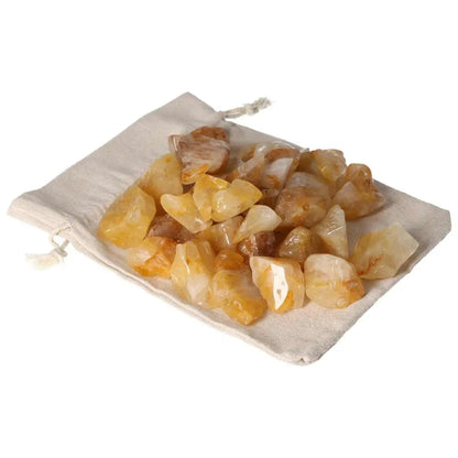 Assorted tumbled yellow hematoid crystals on a beige cloth showcasing their golden hues, representing luxury and elegance.