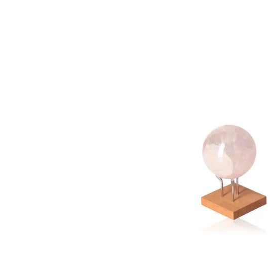 Sylvia Crystals' Pink Quartz Sphere on wooden stand, symbolizing love, elegance, and spiritual connection; crafted from natural, ethical quartz.
