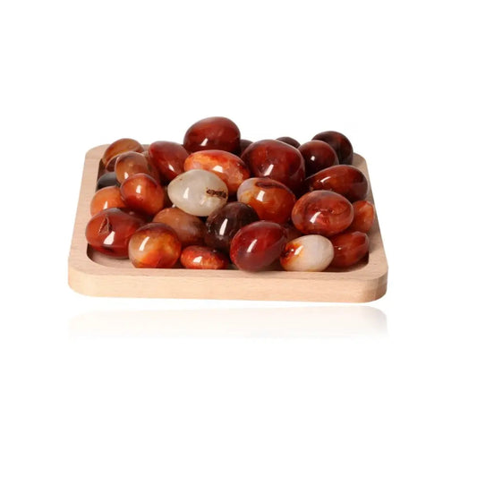 Carnelian palm stones on a wooden tray, showcasing vibrant orange-red hues; ideal for motivation and energy enhancement.