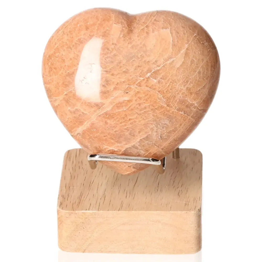 Peach Moonstone Heart for emotional balance and intuition on a wooden stand, enhances attractiveness and protects against nightmares.
