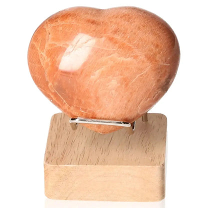 Peach Moonstone Heart on wooden stand, promoting emotional balance, stimulating intuition, and offering protection for restful sleep.