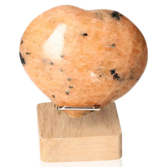 Peach Moonstone Heart crystal promoting emotional balance, intuition, and protection from nightmares on a wooden stand.
