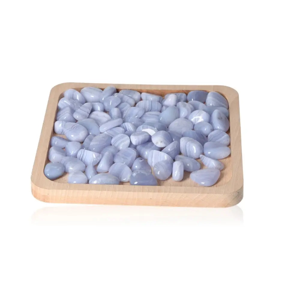 Tumbled Blue Chalcedony stones arranged on wooden tray for emotional balance and tranquility.
