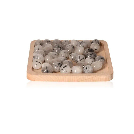 Tumbled black tourmaline in quartz stones on a wooden tray, showcasing their striking appearance and protective energies.