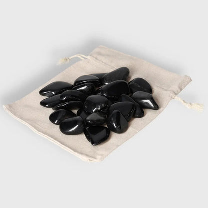 Tumbled Obsidian stones in beige pouch, known for protective energy and aura, absorbing negativity for a serene environment.
