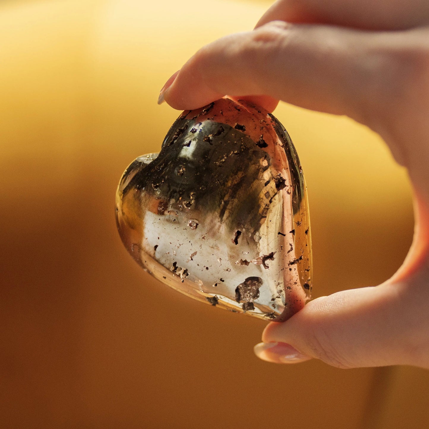 Close-up of a hand holding a heart-shaped quartz geode with pyrite inclusions, symbolizing love and abundance, ideal for Valentine’s Day.