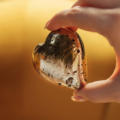 Close-up of a hand holding a heart-shaped quartz geode with pyrite inclusions, symbolizing love and abundance, ideal for Valentine’s Day.