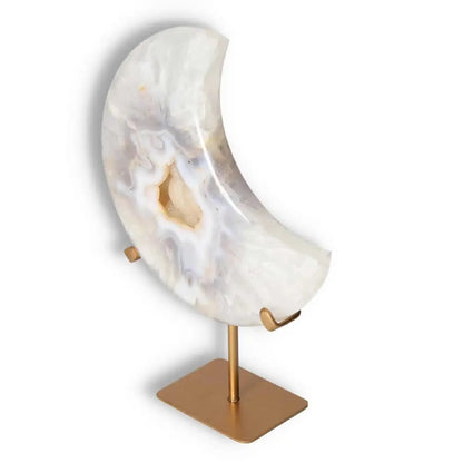 Ethereal agate lunar crescent sculpture with natural geode, showcasing swirling off-white hues, displayed on a sleek gold stand.