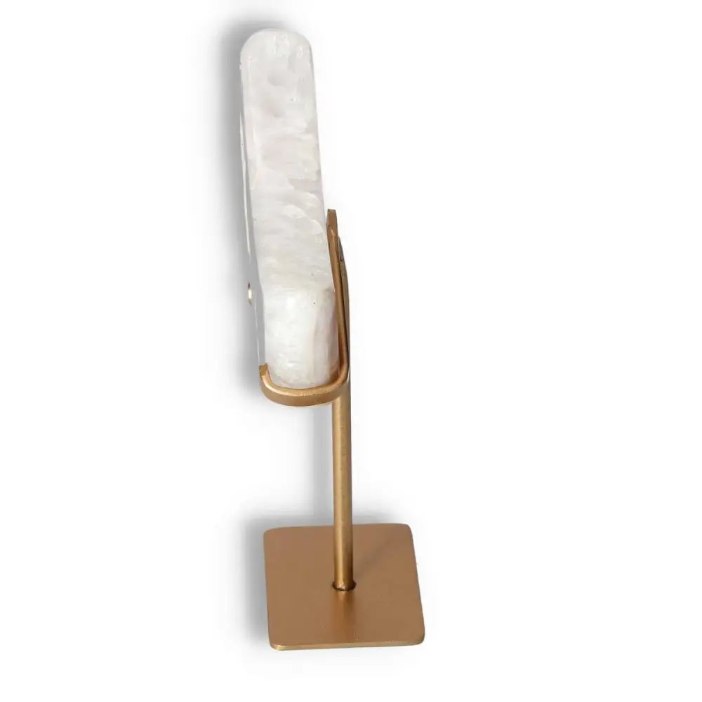 Side view of agate lunar crescent sculpture on a stand, displaying natural geode formation and white swirls of translucent agate.