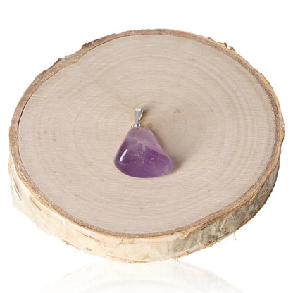 Amethyst Tumbled Pendant featuring a polished amethyst stone, displayed elegantly on a wooden slice, showcasing natural elegance and tranquility.