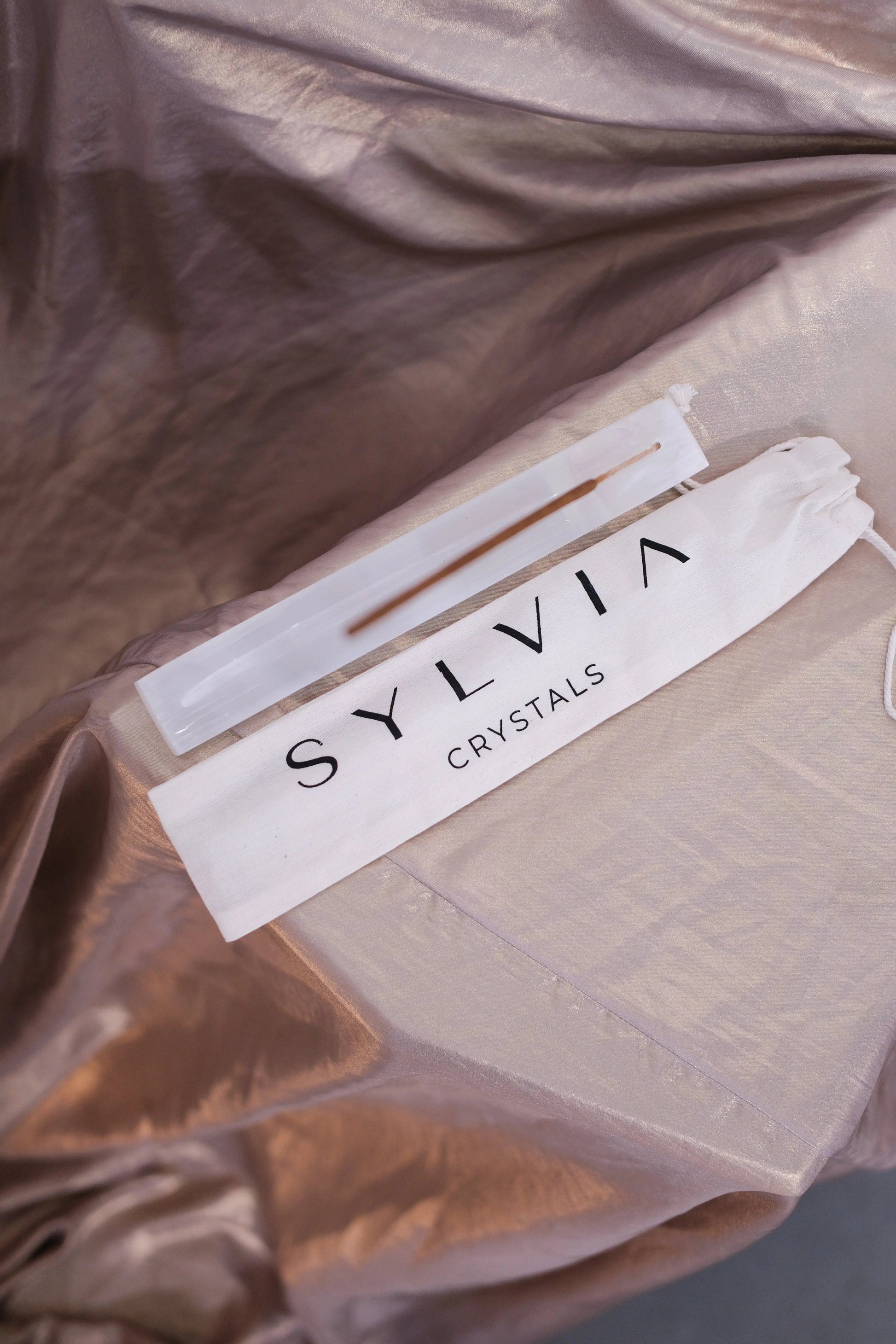 Selenite crystal wand with 'SYLVIA CRYSTALS' pouch on satin fabric