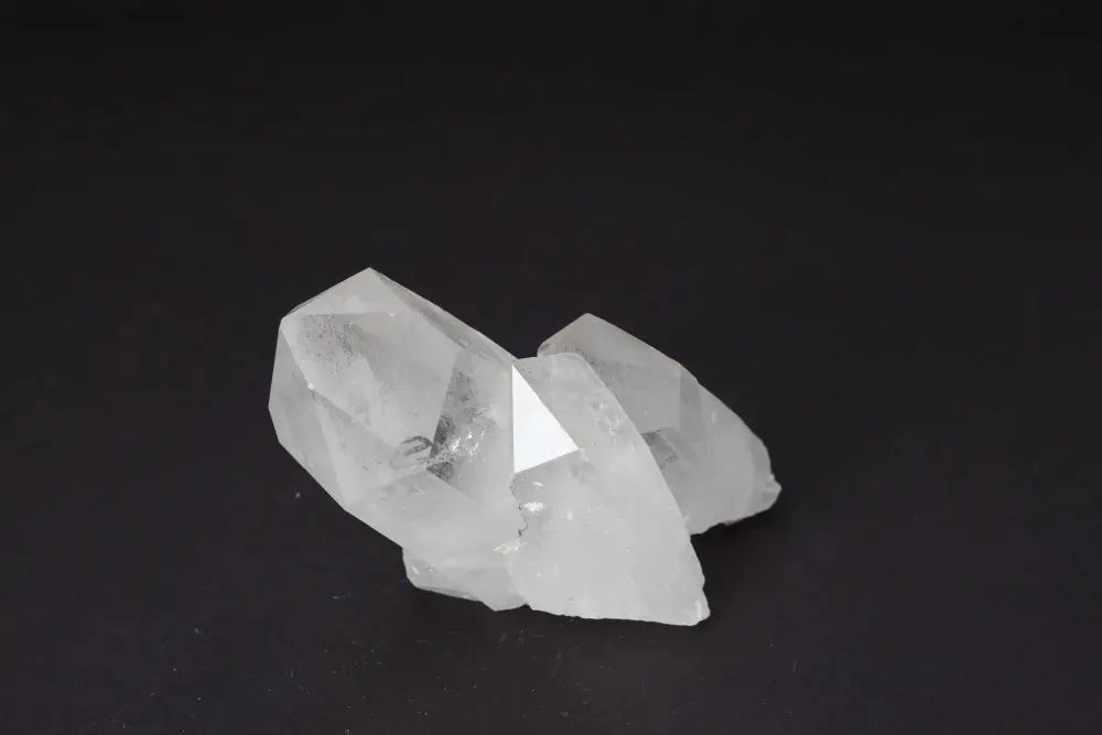Clear Quartz Cluster radiating energy with multiple crystal points on dark background, amplifying purity and harmony in space.
