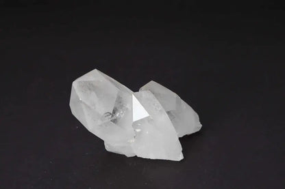Clear Quartz Cluster radiating energy with multiple crystal points on dark background, amplifying purity and harmony in space.